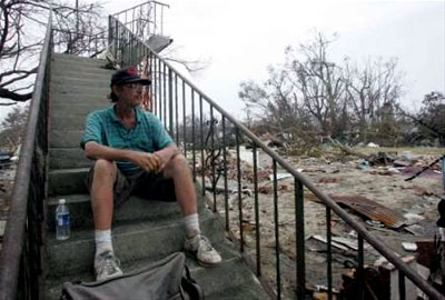 Stairs to Nowhere: A reflective Hurricane Katrina survivor sits on a staircase next to a destroyed building