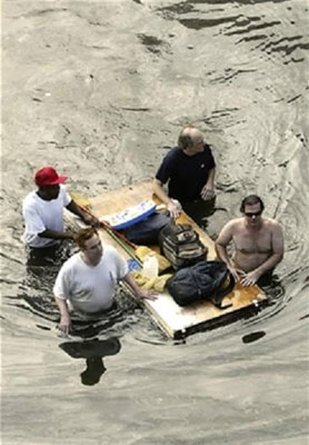 Four Hurricane Katrina survivors transport some personal items on a makeshift float
